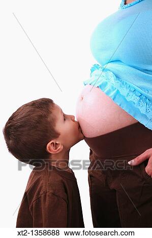 Stock Photo - A young boy kisses his mothers pregnant stomache, isolated on white background. Fotosearch
