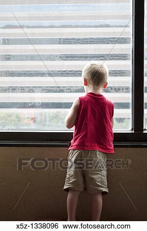 A young boy looking out a high window View Large Photo Image Stock Photograph - A young boy looking out a high window. Fotosearch