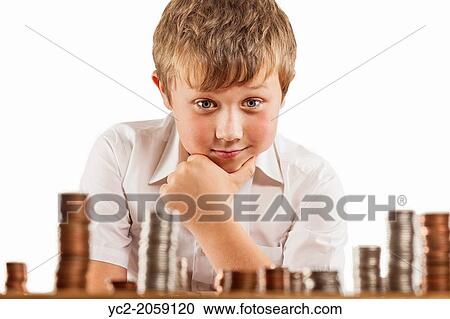 Stock Image - A young boy of 10 counts his money and stacks it up.. Fotosearch