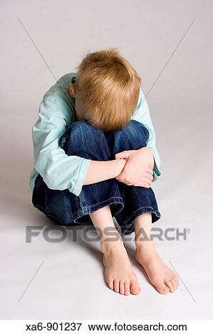 A young boy sits hunched over hugging his bent legs and hiding his face View Large Photo Image Stock Photo - A young boy sits hunched over hugging his bent legs and hiding his face. Fotosearch