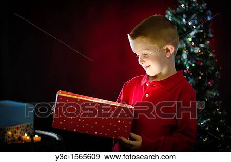 A young boy unwrapping a gift at Christmas morning or on Christmas Eve View Large Photo Image Stock Photo - A young boy unwrapping a gift at Christmas morning or on Christmas Eve. Fotosearch