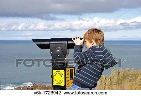 Stock Image - a young boy using a telescope at lands end in cornwall, england, uk. Fotosearch