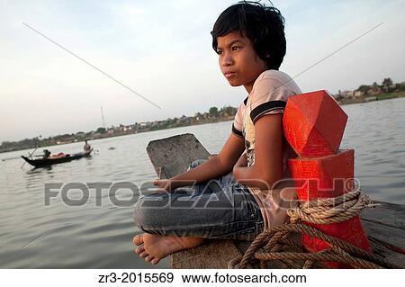 A young boy watches fisherman at work on the Mekong River early in the morning outside of Phnom Penh, Cambodia. View Large Photo Image Stock Photo - A young boy watches fisherman at work on the Mekong River early in the morning outside of Phnom Penh, Cambodia.. Fotosearch