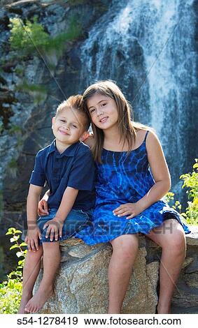 A young brother and sister sitting together outdoors View Large Photo Image Stock Photo - A young brother and sister sitting together outdoors. Fotosearch