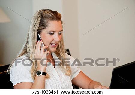 A young business woman working on her computer at a desk View Large Photo Image Stock Image - A young business woman working on her computer at a desk. Fotosearch