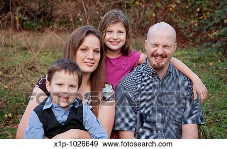 A young Caucasian family of 4 portrait outdoors, dad is laughing. Two kids, boy and girl with mom and dad. View Large Photo Image Stock Photo - A young Caucasian family of 4 portrait outdoors, dad is laughing. Two kids, boy and girl with mom and dad.. Fotosearch
