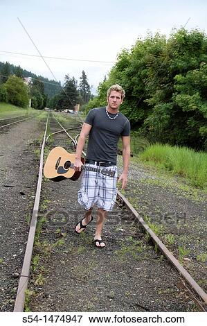 A young caucasian male with his guitar outdoors View Large Photo Image Stock Photo - A young caucasian male with his guitar outdoors. Fotosearch