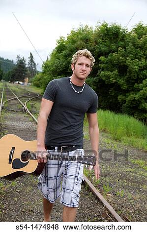 A young caucasian male with his guitar outdoors View Large Photo Image Stock Photo - A young caucasian male with his guitar outdoors. Fotosearch