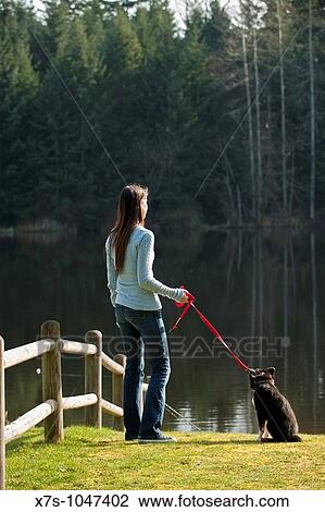 Stock Image - A young Caucasian woman and her puppy dog at the park. Fotosearch