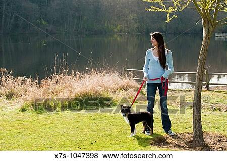 Stock Photo - A young Caucasian woman and her puppy dog at the park. Fotosearch