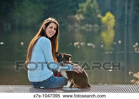 Stock Photography - A young Caucasian woman and her puppy dog at the park. Fotosearch