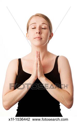 Stock Image - a young caucasian woman looking angelic and praying with her hands together. Fotosearch