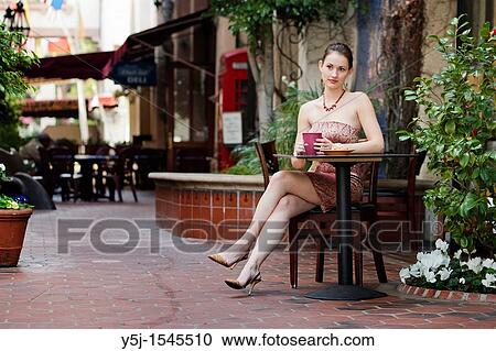 Stock Image - A young Caucasian woman sitting alone drinking an espresso. Fotosearch