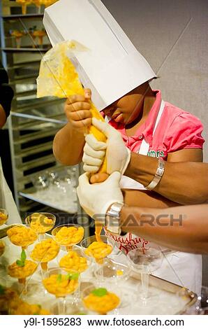 Stock Image - A young chef pipes the pumpkin pudding dessert Children participating in Nourishing NYC? s Junior Chef program prepare a healthy Thanksgiving dinner in midtown in New York. Fotosearch