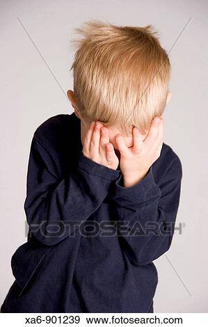 Stock Photo - A young child hides his face in his hands. Fotosearch