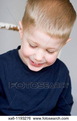 Stock Photograph - A young child smiling and looking down. Fotosearch