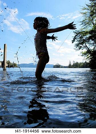 Stock Photograph - A young child splashing in a lake in New Hampshire. Fotosearch