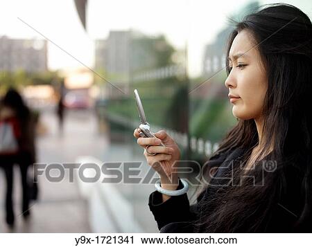 A young Chinese business woman using her mobile phone in the city View Large Photo Image Stock Image - A young Chinese business woman using her mobile phone in the city. Fotosearch