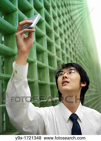 A young Chinese businessman uses his mobile phone to take a picture. View Large Photo Image Stock Photo - A young Chinese businessman uses his mobile phone to take a picture.. Fotosearch
