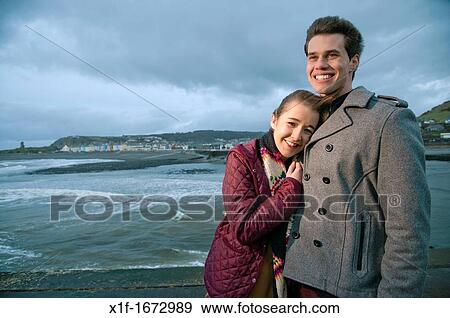 A young couple, boyfriend and girlfriend, together on a windy afternoon on the seashore, west wales UK View Large Photo Image Stock Photo - A young couple, boyfriend and girlfriend, together on a windy afternoon on the seashore, west wales UK. Fotosearch