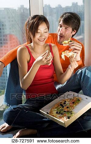 a young couple drinking and eating pizza View Large Photo Image Stock Image - a young couple drinking and eating pizza. Fotosearch