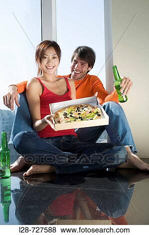 Stock Photo - a young couple drinking and eating pizza. Fotosearch