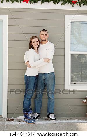 A young couple hugging outdoors by a house View Large Photo Image Stock Photo - A young couple hugging outdoors by a house. Fotosearch