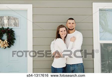 A young couple hugging outdoors by a house View Large Photo Image Stock Photograph - A young couple hugging outdoors by a house. Fotosearch