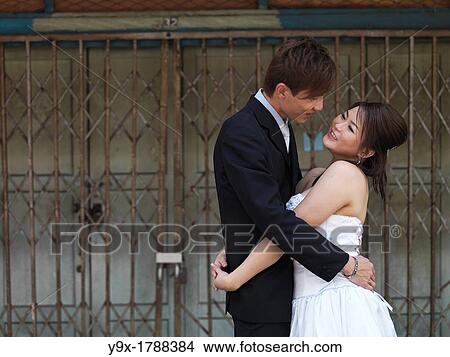 A young couple in wedding attire embraces playfully in Johor, Malaysia View Large Photo Image Picture - A young couple in wedding attire embraces playfully in Johor, Malaysia. Fotosearch