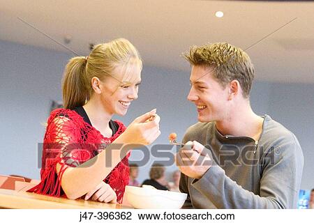 A young couple sitting in a cafe sharing a bowl of fruit smiling and laughing together View Large Photo Image Stock Image - A young couple sitting in a cafe sharing a bowl of fruit smiling and laughing together. Fotosearch