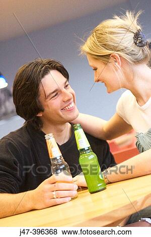 A young couple sitting in a cafe with drinks, smiling at each other View Large Photo Image Stock Photo - A young couple sitting in a cafe with drinks, smiling at each other. Fotosearch