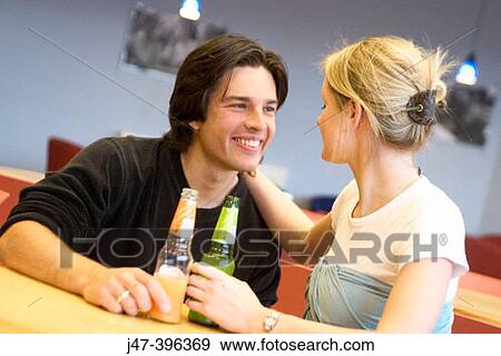 A young couple sitting in a cafe with drinks, smiling at each other View Large Photo Image Stock Photo - A young couple sitting in a cafe with drinks, smiling at each other. Fotosearch