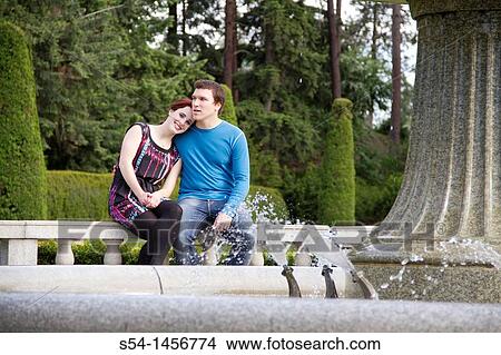 A young couple sitting together outdoors View Large Photo Image Picture - A young couple sitting together outdoors. Fotosearch