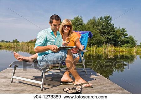 A young couple studying a magazine at a lake, Germany, Europe View Large Photo Image Stock Photo - A young couple studying a magazine at a lake, Germany, Europe. Fotosearch