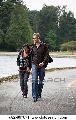 Stock Image - A young couple walking along the seawall at Stanley Park, Vancouver, British Columbia, Canada. Fotosearch