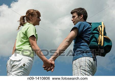 Stock Photograph - A young couple walking hand in hand. Fotosearch