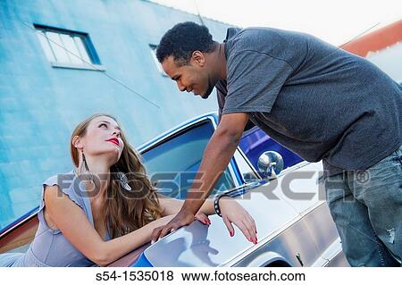 Stock Photo - A young couple with their 1964 Chevrolet Impala. Fotosearch