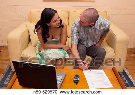 Stock Image - A young couple working together at home.. Fotosearch