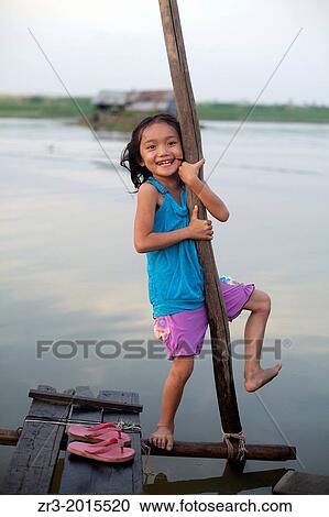 Stock Image - A young girl plays by the river in a small village outside of Phnom Penh, Cambodia.. Fotosearch