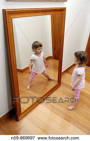 A young girl, two and a half years old, playing in front of a large mirror View Large Photo Image Stock Photo - A young girl, two and a half years old, playing in front of a large mirror. Fotosearch