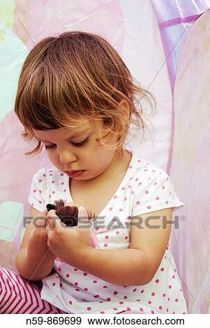 Stock Photo - A young girl, two and a half years old, playing with a doll. Fotosearch