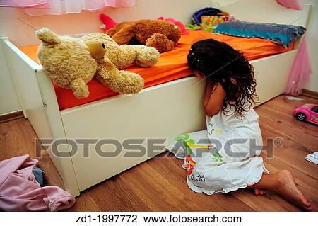Stock Image - A young girl who is a victim of domestic violence cries on the floor of her bedroom.. Fotosearch