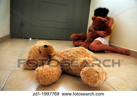 A young girl who is a victim of domestic violence sits on the floor next to the front door and gets comfort from her teddy bears. View Large Photo Image Stock Photo - A young girl who is a victim of domestic violence sits on the floor next to the front door and gets comfort from her teddy bears.. Fotosearch