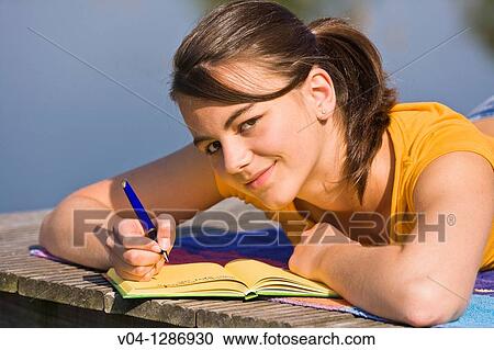 A young girl writing into her diary at a lake, smiling at the camera View Large Photo Image Stock Image - A young girl writing into her diary at a lake, smiling at the camera. Fotosearch