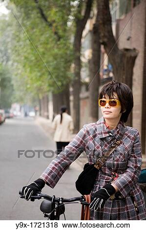 A young, hip urban Beijing woman walks her bicycle down the street in the SanLiTun bar district View Large Photo Image Stock Photo - A young, hip urban Beijing woman walks her bicycle down the street in the SanLiTun bar district. Fotosearch
