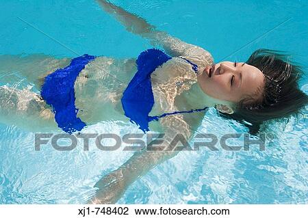 A young Japanese woman floating in a swimming pool. View Large Photo Image Stock Image - A young Japanese woman floating in a swimming pool.. Fotosearch