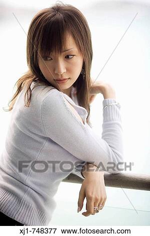 A young Japanese woman leans against a deck railing outside her hotel room. View Large Photo Image Stock Photo - A young Japanese woman leans against a deck railing outside her hotel room.. Fotosearch
