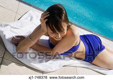 A young Japanese woman lying on a towell beside a hotel complex swimming pool. View Large Photo Image Stock Photo - A young Japanese woman lying on a towell beside a hotel complex swimming pool.. Fotosearch