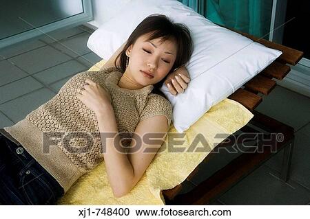 Stock Image - A young Japanese woman resting on a sunchair outside her hotel room. Fotosearch