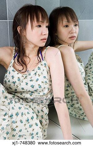 Stock Image - A young Japanese woman sits on a hotel bathroom vanity unit.. Fotosearch
